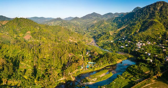 Aerial image of a Rainforest with small pockets of human settlements. Understanding and assessing impacts beyond carbon