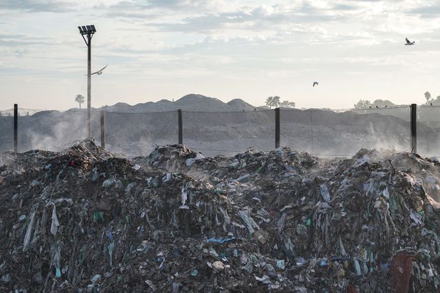 A large landfill site with steam rising from it and seagulls flying overhead